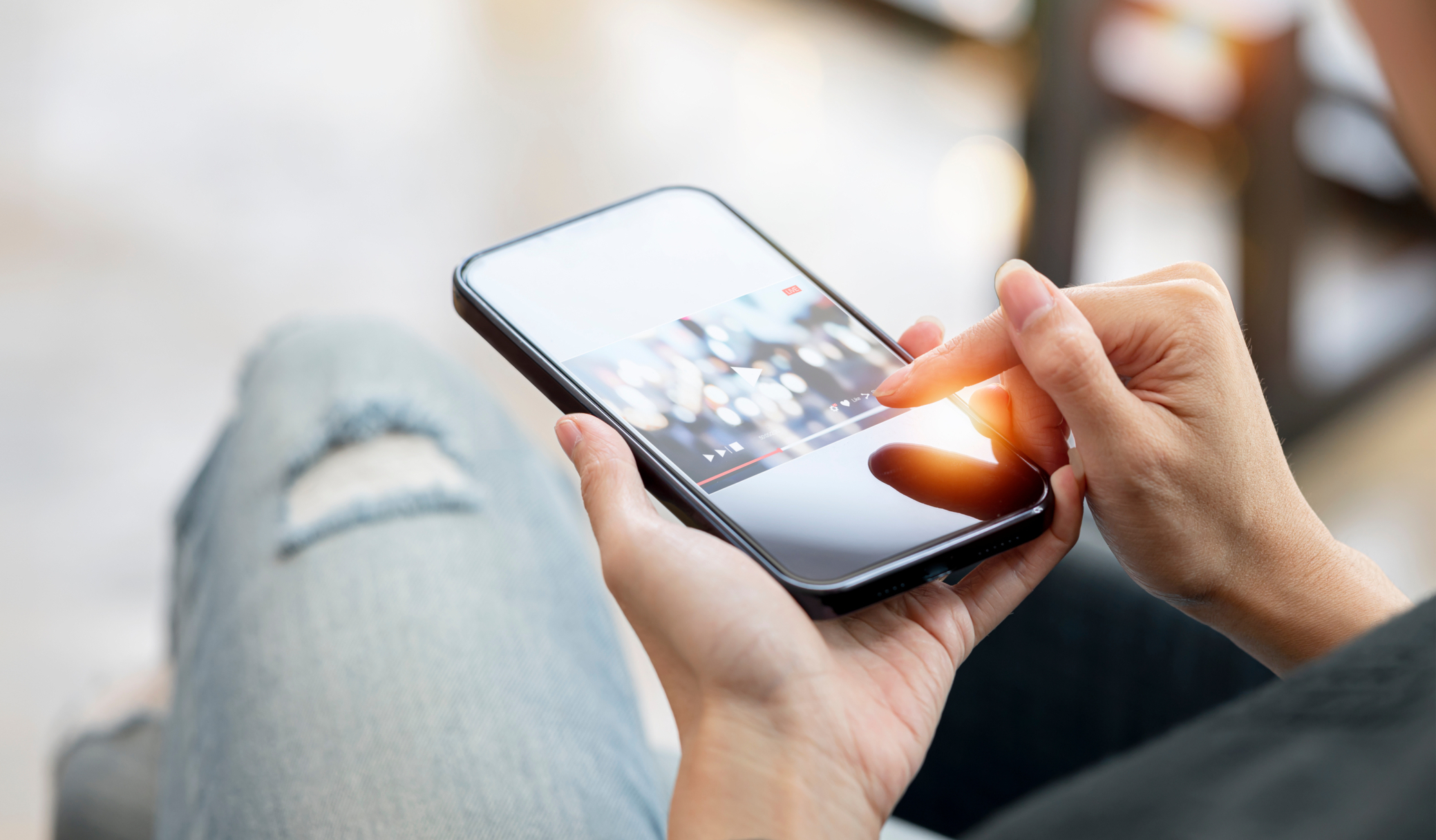 Cropped image of woman hand holding smartphone and watching video with night bokeh background.