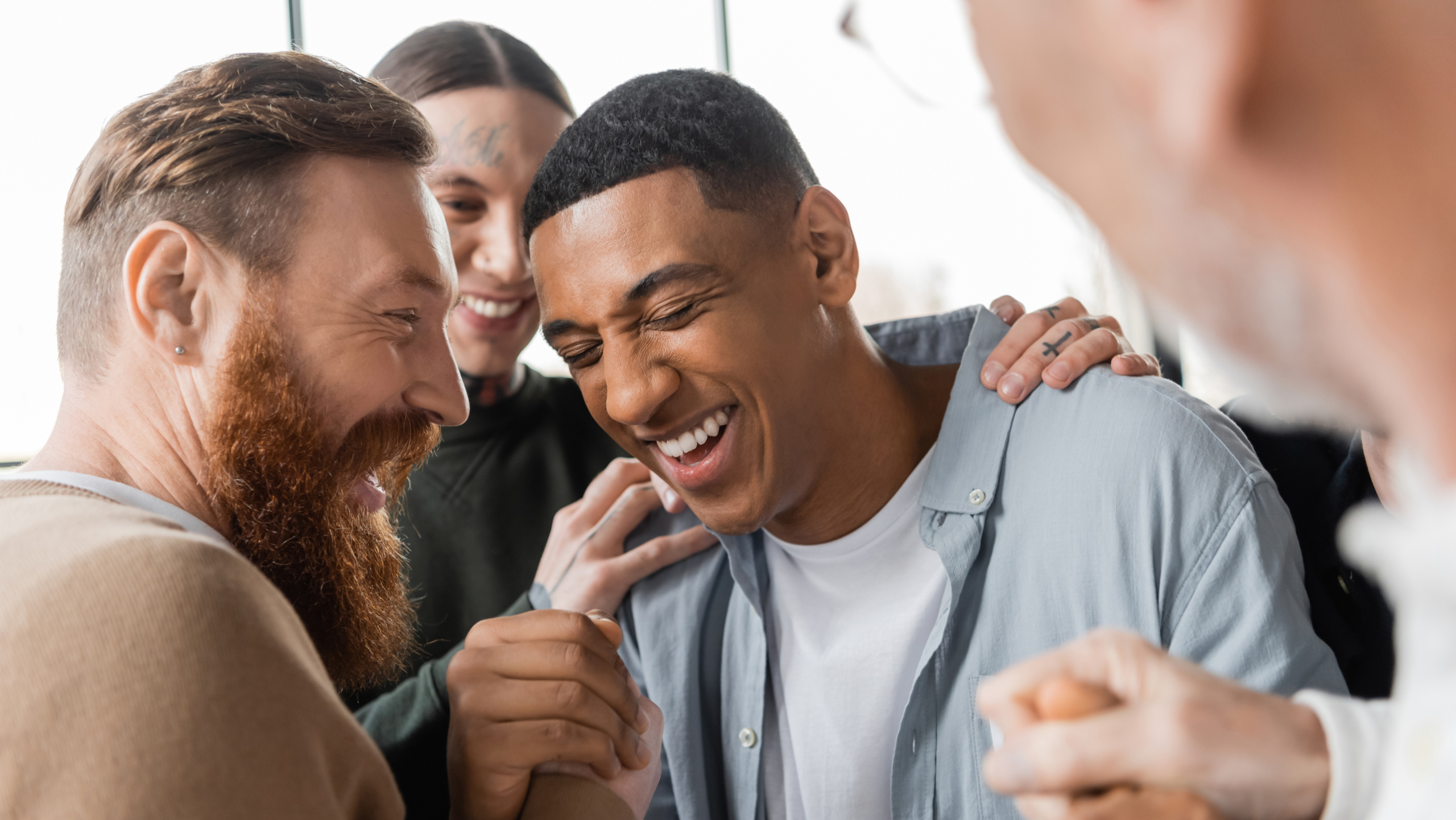 Positive people hugging african american man during alcoholics meeting and therapy in rehab center.